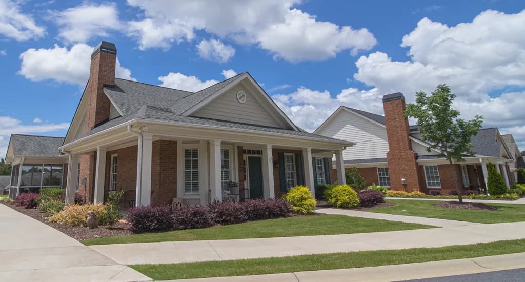 Exterior view of brick cottage homes with front porches and landscaped yards at Cascades Verdae in Greenville, SC.