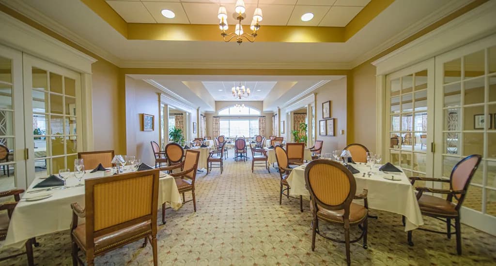 Formal dining room at Cascades Verdae in Greenville, SC, featuring tables with white tablecloths and warm lighting.