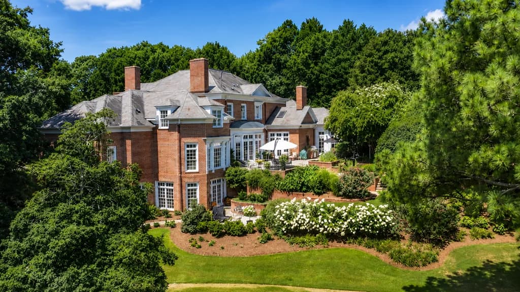 A large luxury brick home in the Chanticleer community of Greenville, SC, featuring a landscaped garden and patio.