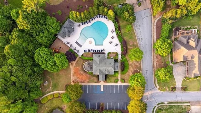 Aerial view of the Claremont community clubhouse, swimming pool, and parking area nestled in trees.