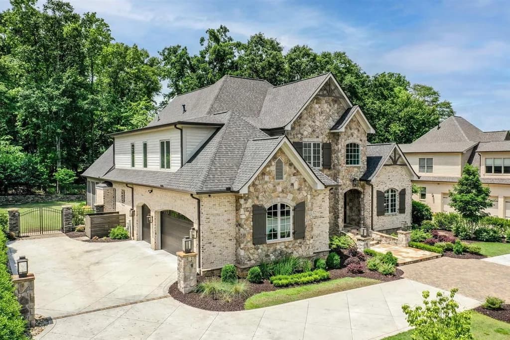 A large stone and brick luxury estate home in the Claremont community with a multi-car garage and manicured lawn.