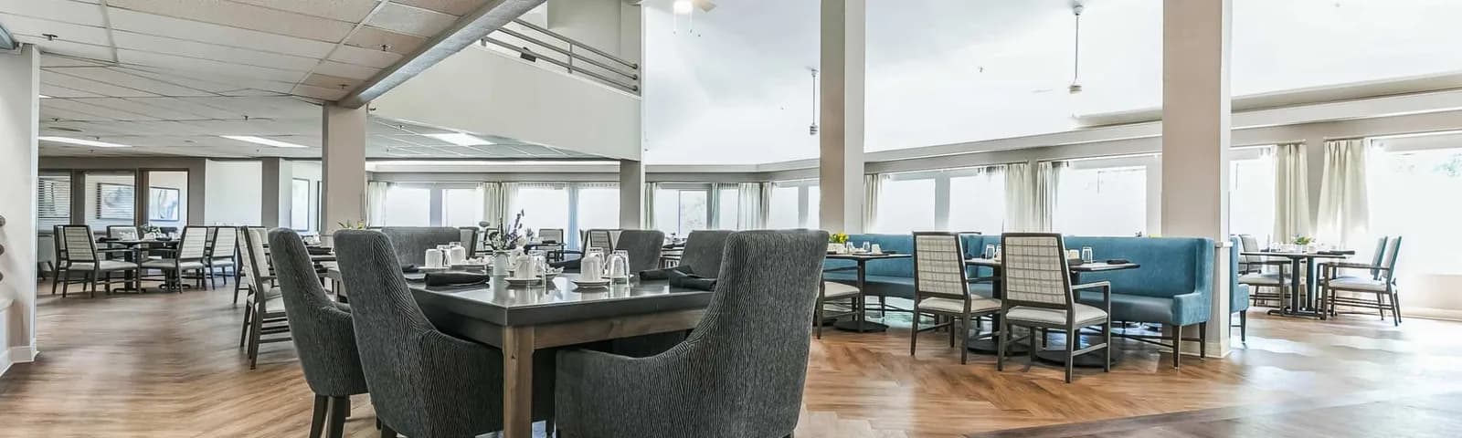 Bright dining room at Haywood Estates in Greenville with blue banquette seating and large windows.