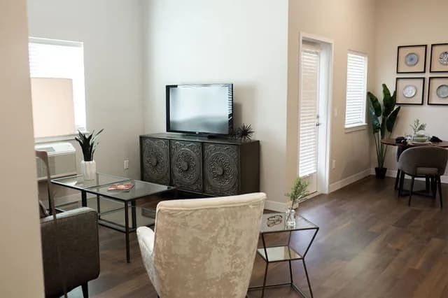 Open living and dining room in a Maple Brook Terrace apartment, featuring modern furniture and wood-style flooring.