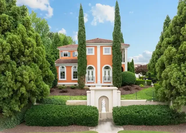 Mediterranean-style home in the Montebello community in Greenville, SC, featuring an orange exterior and cypress trees.