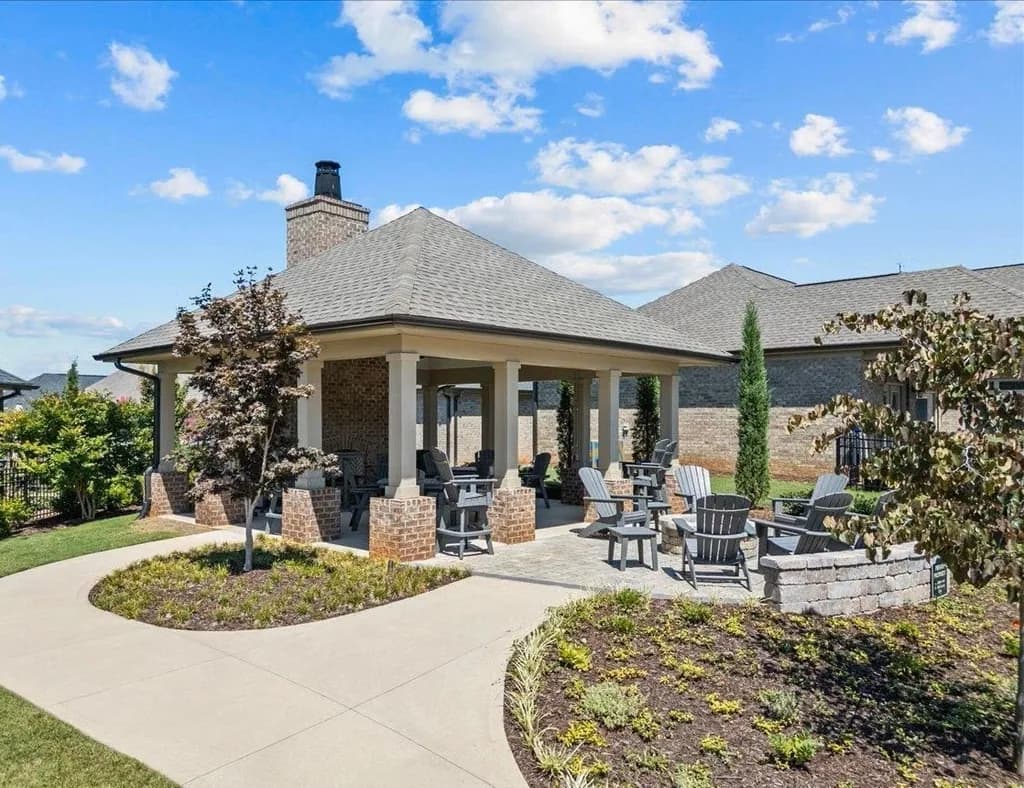 Outdoor brick pavilion with a fireplace and Adirondack chair seating area in the Paxton-Meadows 55+ community.