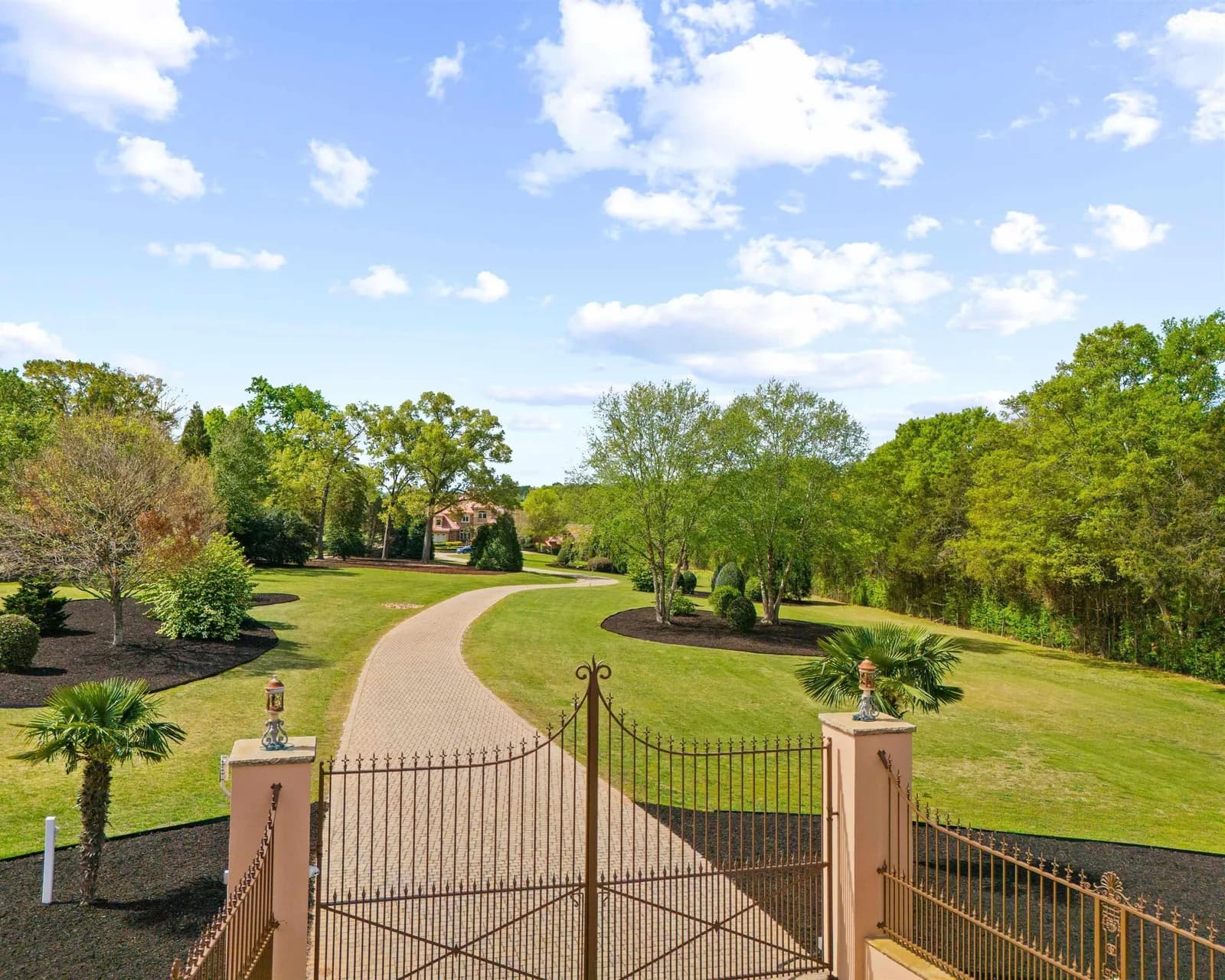 A wrought-iron gate leading to a long driveway at the entrance of The Ravines at Creekside 55+ community.