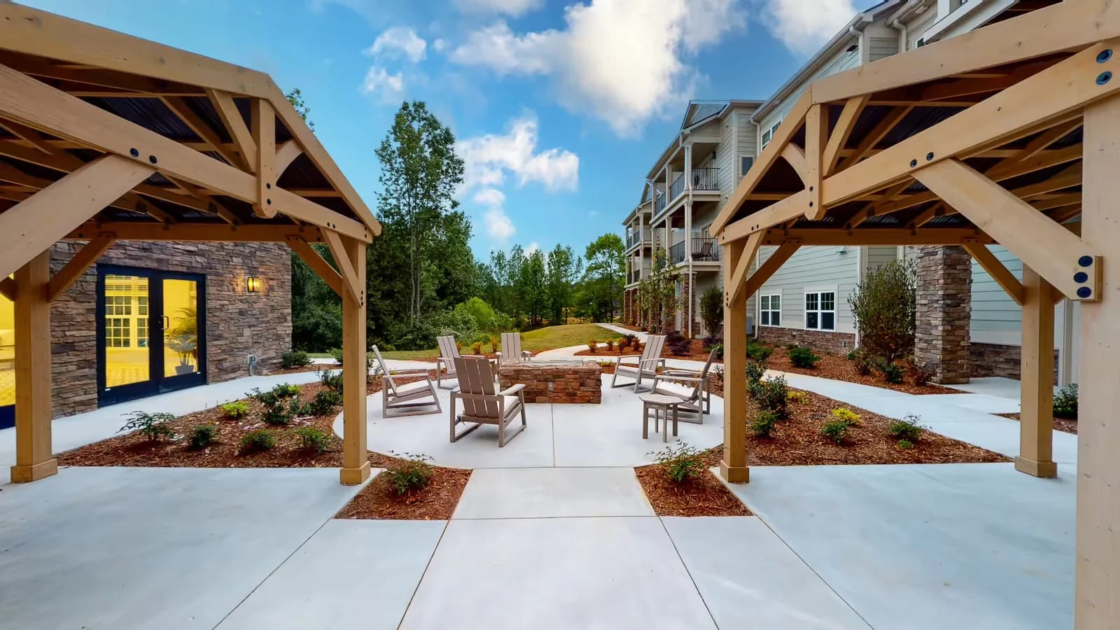 Outdoor fire pit and lounge area with seating under a pergola at Ravines at Creekside 55+ community.