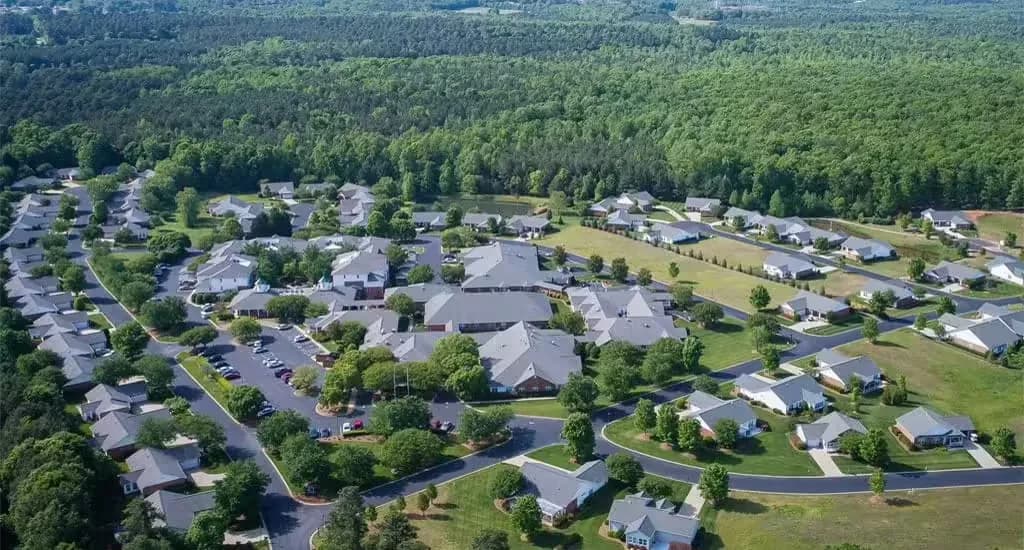 Aerial view of the Ravines at Woodridge 55+ community showing residential homes, roadways, and greenery.
