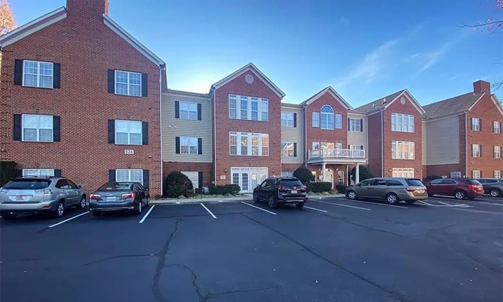 Exterior view of the Ravines at Woodridge 55+ community showing the brick apartment building and parking lot.