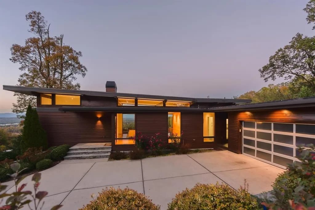 Modern custom home at dusk in The Ridges at Paris Mountain with horizontal wood siding and geometric architecture.