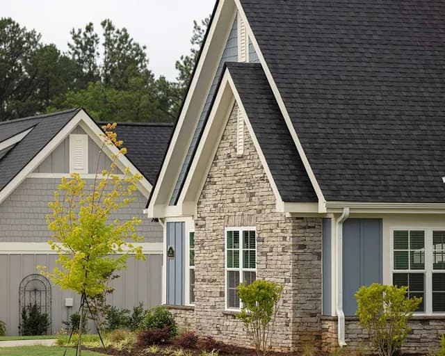 Exterior view of a residential home at The Woodlands at Furman in Greenville, SC, featuring stone and siding.